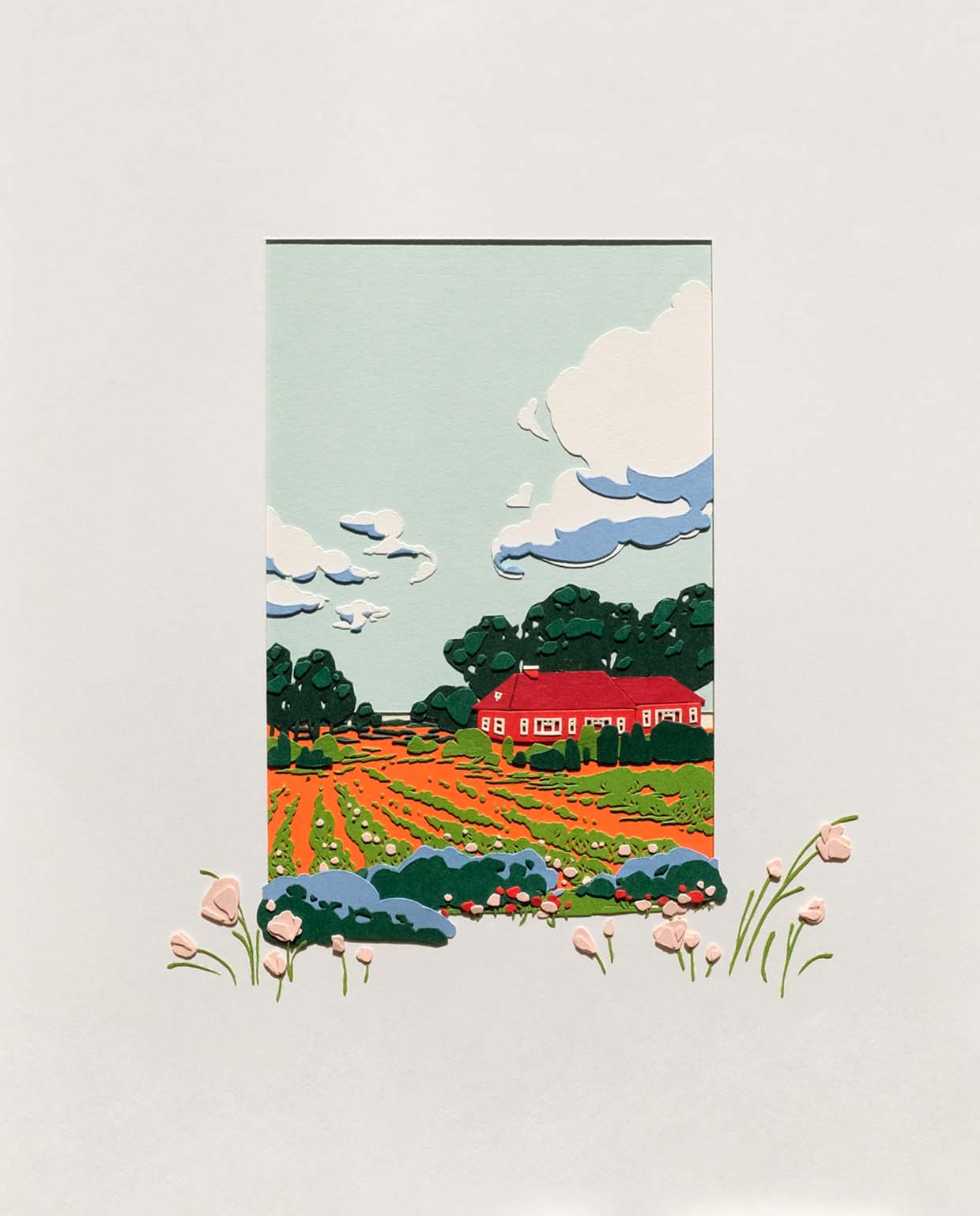 A window in a sheet of white paper reveals a red paper building with white windowsills set amongst a green and orange field bordered by green shrubs and trees. Fluffy clouds float by in a light blue sky. Some pink and flowers on delicate green stems are layered outside the white paper window.