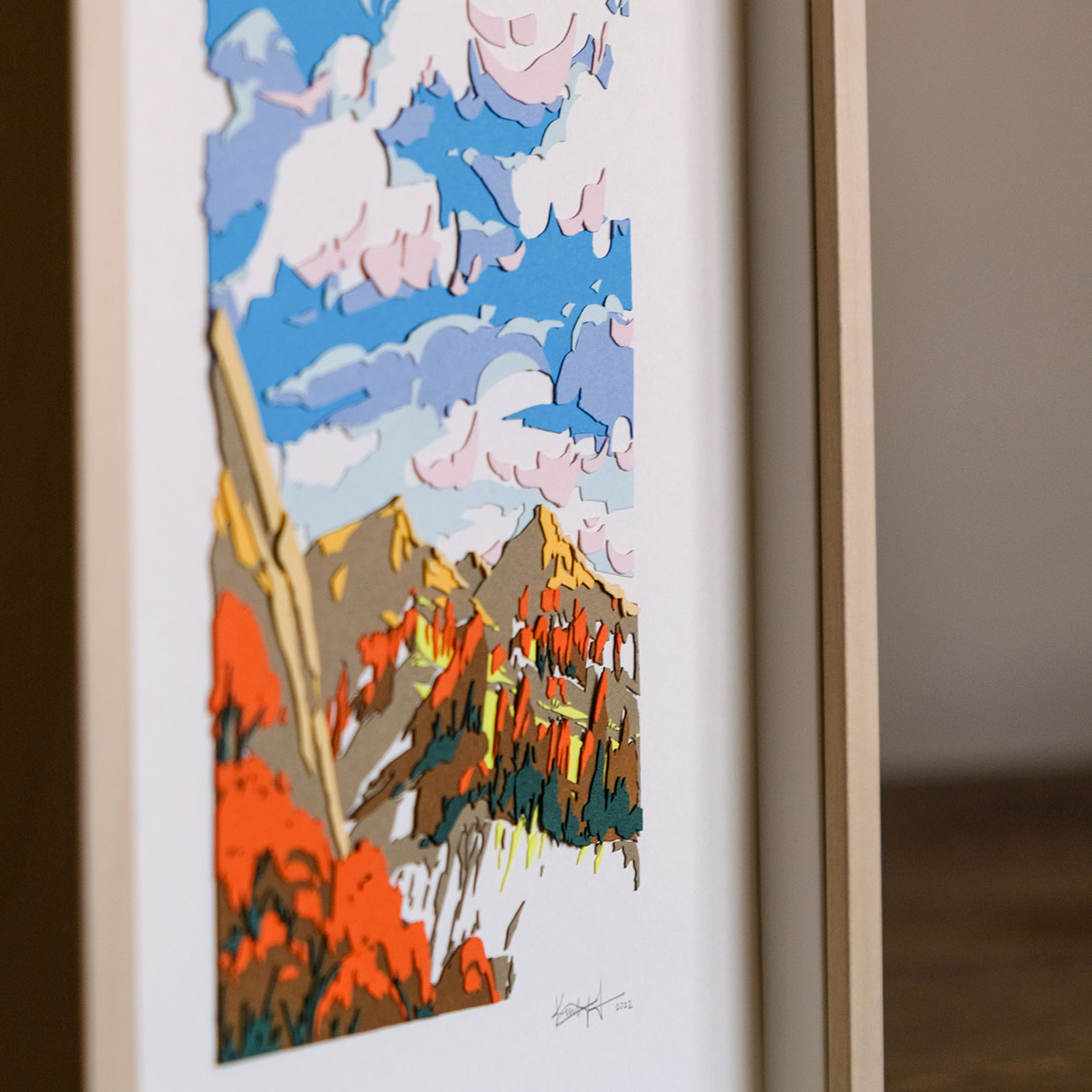 An angled detail view of the artwork reveals the many abstracted layers of paper that form the trees, mountains, and clouds.